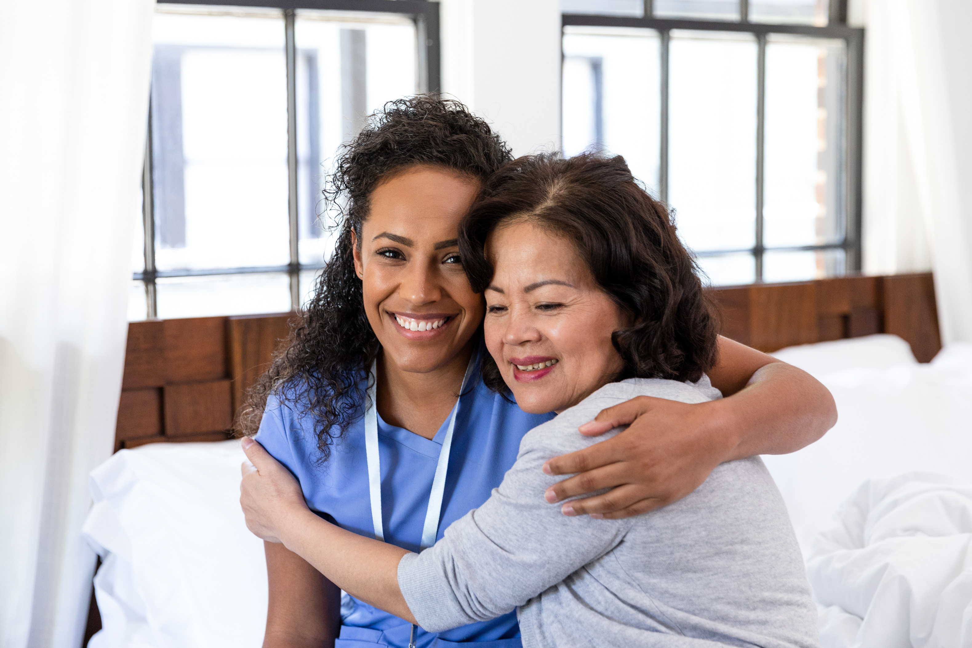 Home healthcare nurse hugs her senior patient